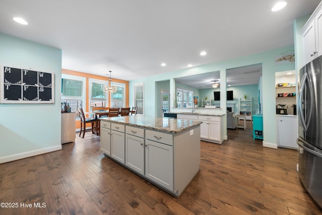 kitchen featuring dark hardwood / wood-style floors, stainless steel fridge, a kitchen island, pendant lighting, and white cabinets