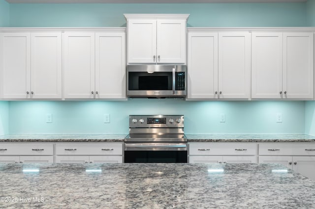 kitchen with appliances with stainless steel finishes, white cabinets, and light stone counters