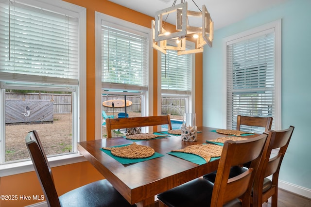 dining space with plenty of natural light, hardwood / wood-style floors, and an inviting chandelier