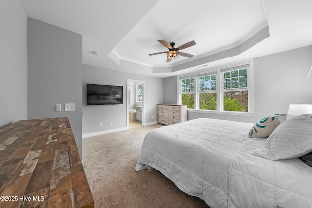 bedroom featuring crown molding, ensuite bath, a tray ceiling, ceiling fan, and carpet