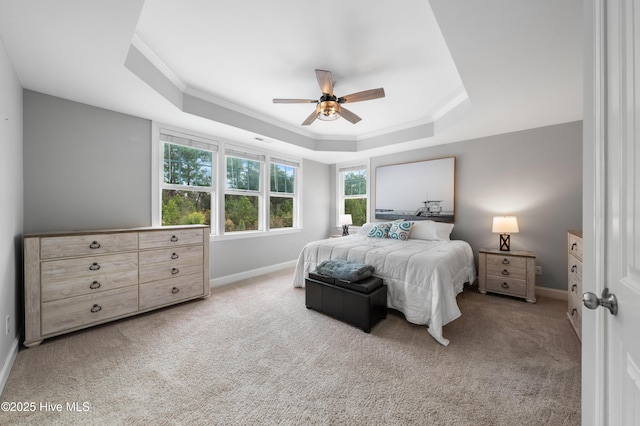 carpeted bedroom with crown molding, a tray ceiling, and ceiling fan