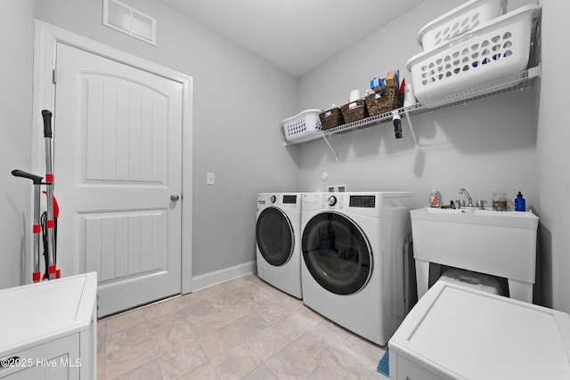 laundry area with separate washer and dryer and sink