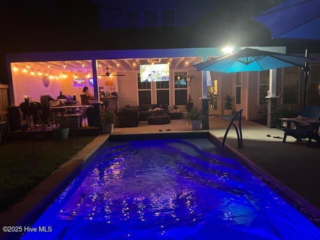 pool at night featuring a patio area