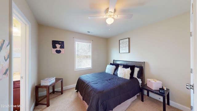 bedroom featuring light carpet, ensuite bathroom, and ceiling fan