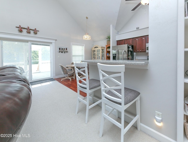 kitchen with pendant lighting, a breakfast bar, high vaulted ceiling, stainless steel appliances, and kitchen peninsula