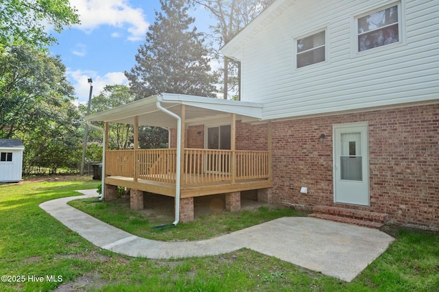 rear view of house featuring a yard, brick siding, a deck, and a patio