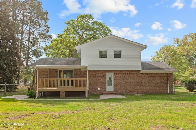 back of property featuring a yard, fence, brick siding, and a shingled roof