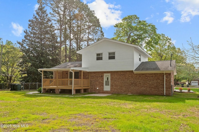 rear view of property featuring brick siding, a deck, fence, and a lawn