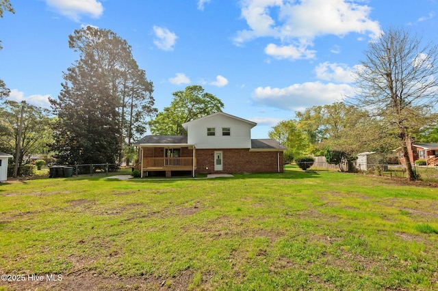 rear view of house with a yard, brick siding, a deck, and fence private yard