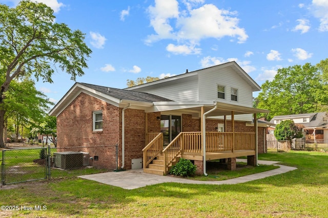 back of house featuring a gate, brick siding, central AC, a yard, and fence