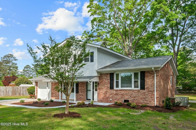 tri-level home featuring a garage, fence, a front lawn, and brick siding
