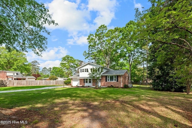 view of front facade with brick siding, a front lawn, and fence