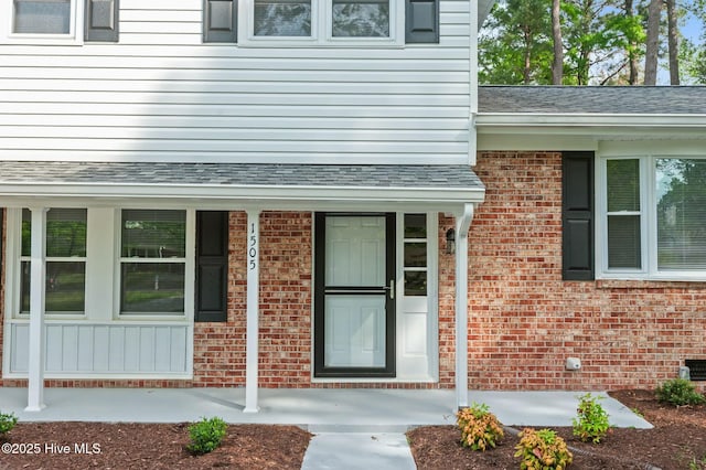 property entrance with brick siding and roof with shingles