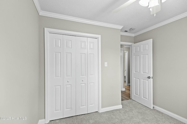 unfurnished bedroom with light carpet, baseboards, ornamental molding, and a closet
