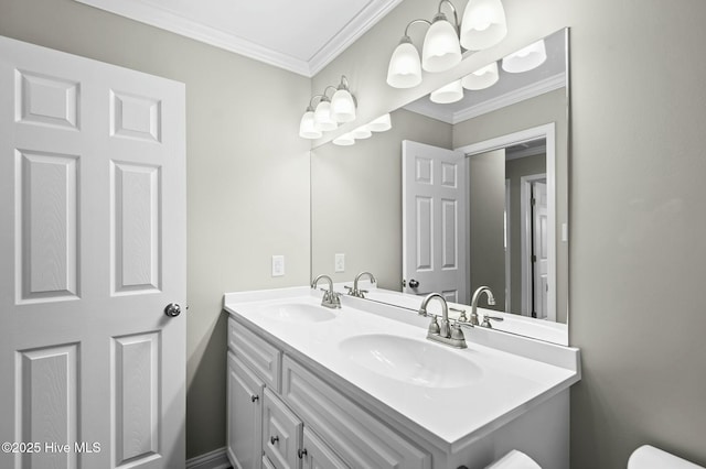 bathroom featuring toilet, double vanity, a sink, and crown molding
