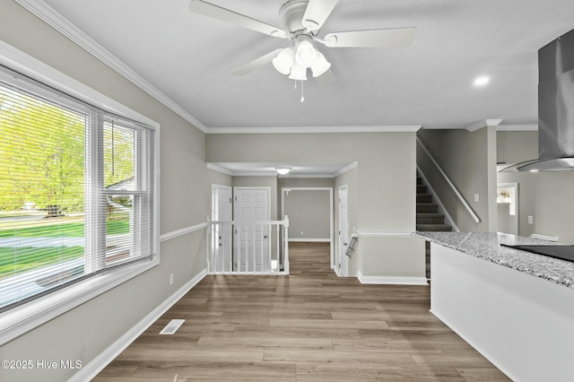 interior space with crown molding, visible vents, a ceiling fan, and wood finished floors