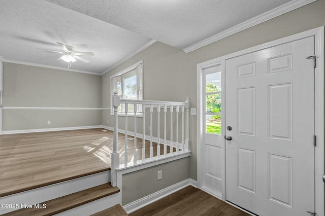 entryway featuring baseboards, ornamental molding, a textured ceiling, ceiling fan, and wood finished floors