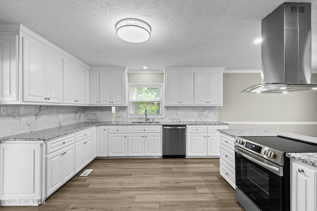 kitchen with light wood-style flooring, white cabinetry, appliances with stainless steel finishes, a sink, and island range hood