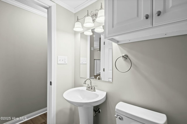 bathroom with crown molding, toilet, wood finished floors, a sink, and baseboards