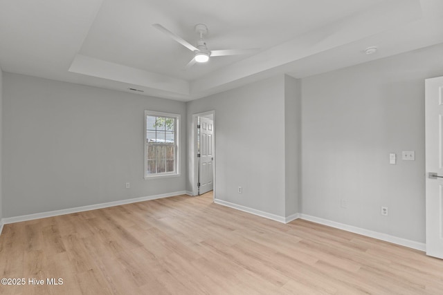 unfurnished room featuring a tray ceiling, light hardwood / wood-style flooring, and ceiling fan