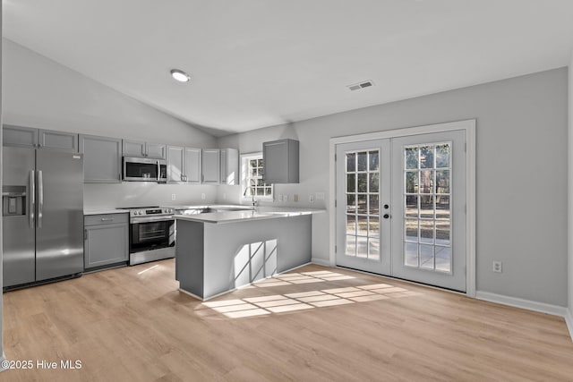 kitchen featuring french doors, light hardwood / wood-style flooring, appliances with stainless steel finishes, gray cabinets, and kitchen peninsula