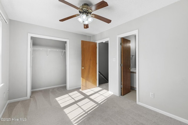 unfurnished bedroom featuring light carpet, a closet, ceiling fan, and ensuite bathroom