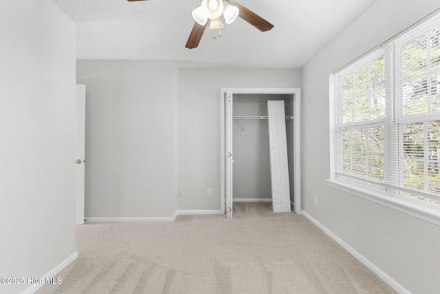 unfurnished bedroom featuring ceiling fan, a closet, light carpet, and a textured ceiling