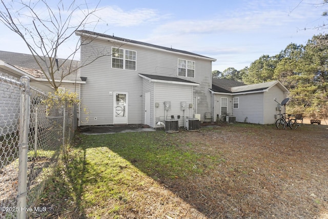 rear view of house with central AC and a lawn