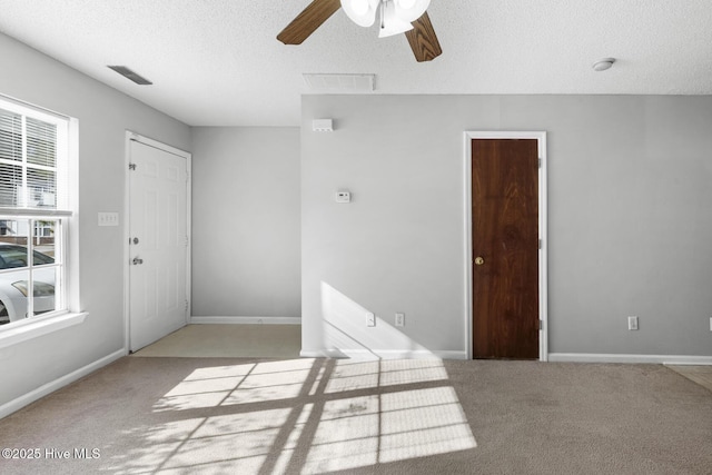 carpeted empty room with ceiling fan and a textured ceiling