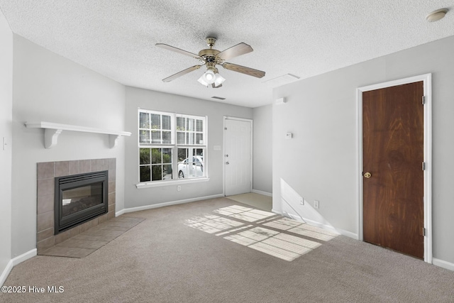 unfurnished living room featuring a tile fireplace, light carpet, a textured ceiling, and ceiling fan