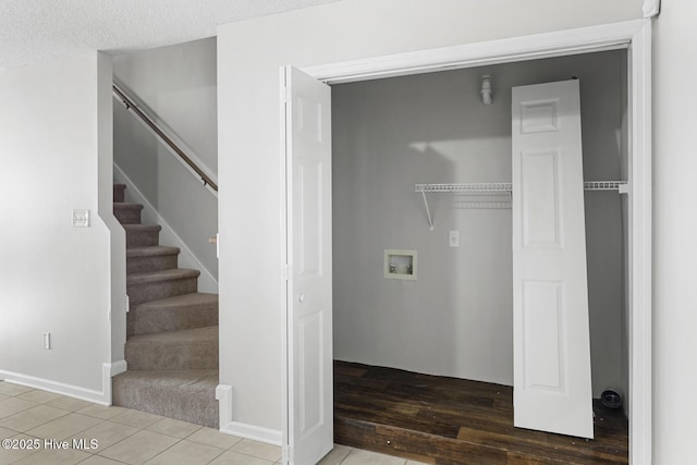 laundry area with tile patterned flooring, washer hookup, and a textured ceiling