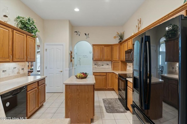 kitchen with light tile patterned flooring, a center island, tasteful backsplash, and black appliances