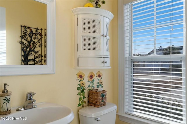 bathroom featuring plenty of natural light, toilet, and sink