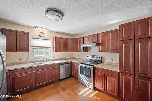 kitchen featuring appliances with stainless steel finishes, sink, hardwood / wood-style floors, and a textured ceiling