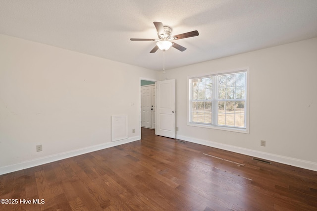 spare room with a textured ceiling, dark wood-type flooring, and ceiling fan