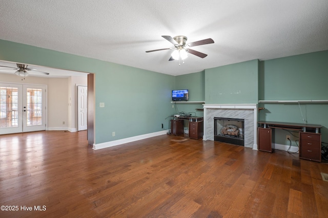 unfurnished living room featuring dark hardwood / wood-style flooring, a fireplace, french doors, and ceiling fan