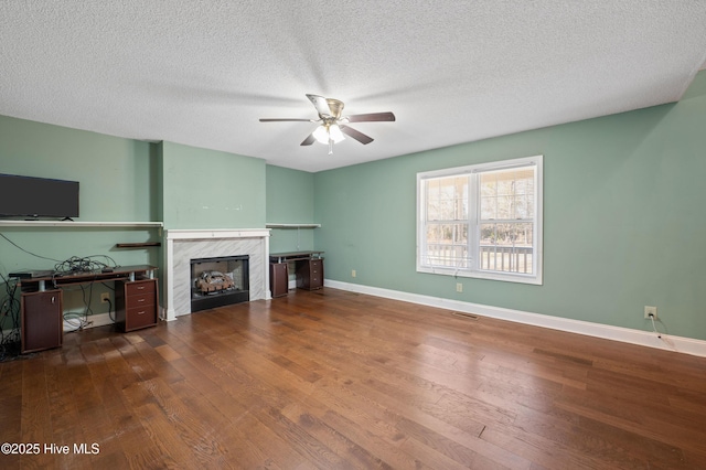 living room featuring ceiling fan, a premium fireplace, dark hardwood / wood-style floors, and a textured ceiling