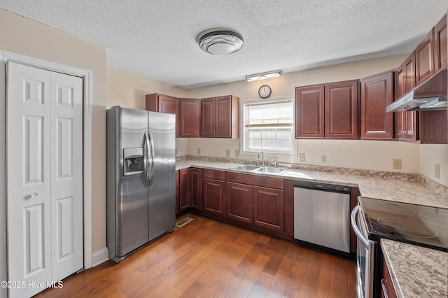 kitchen with sink, hardwood / wood-style flooring, stainless steel appliances, and a textured ceiling