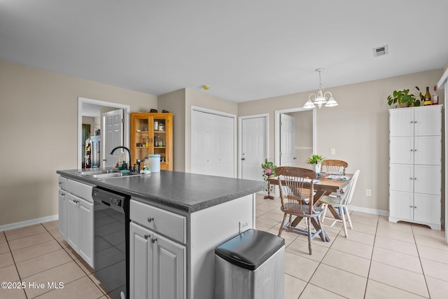 kitchen featuring sink, decorative light fixtures, a center island with sink, light tile patterned floors, and black dishwasher