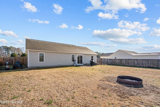 rear view of house with a yard and an outdoor fire pit