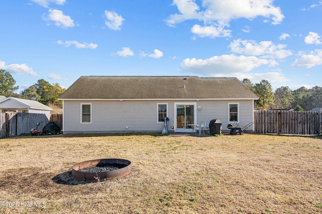 rear view of house featuring a yard and a fire pit