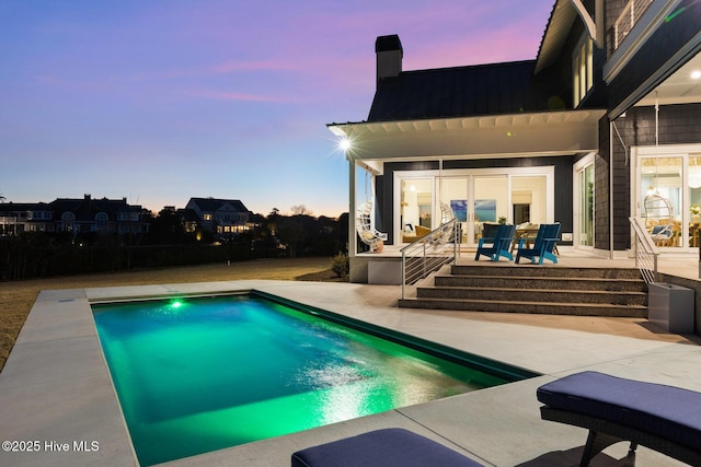 pool at dusk with a patio area