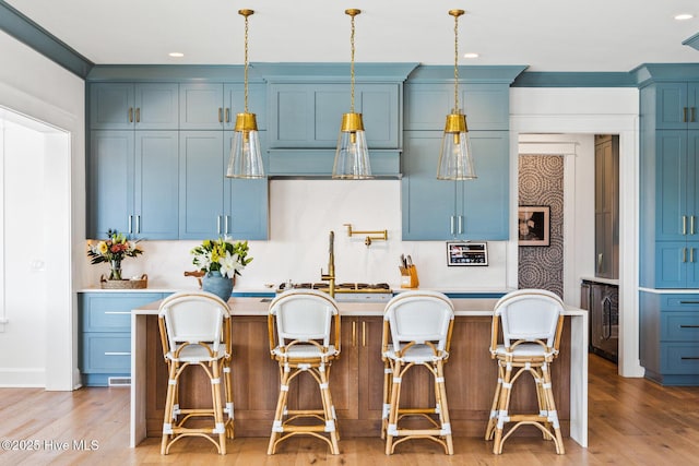 kitchen with light hardwood / wood-style flooring, blue cabinetry, and a kitchen island