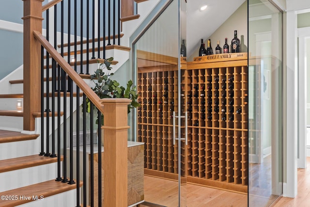 wine room featuring wood-type flooring and vaulted ceiling