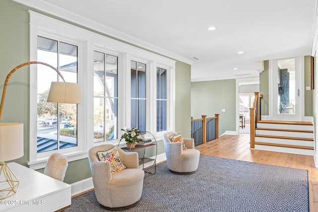 living area featuring crown molding, wood-type flooring, and a wealth of natural light