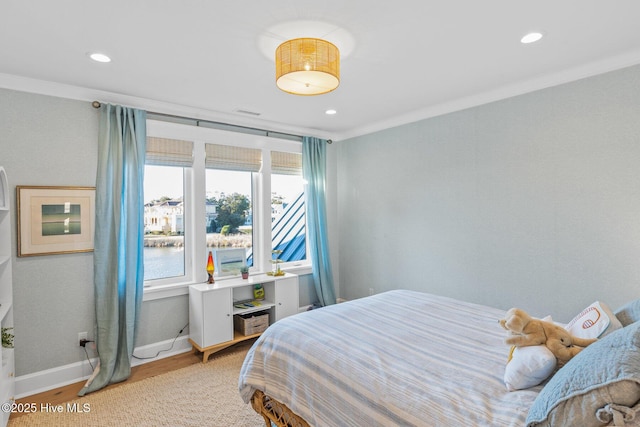 bedroom with ornamental molding, a water view, and light hardwood / wood-style floors