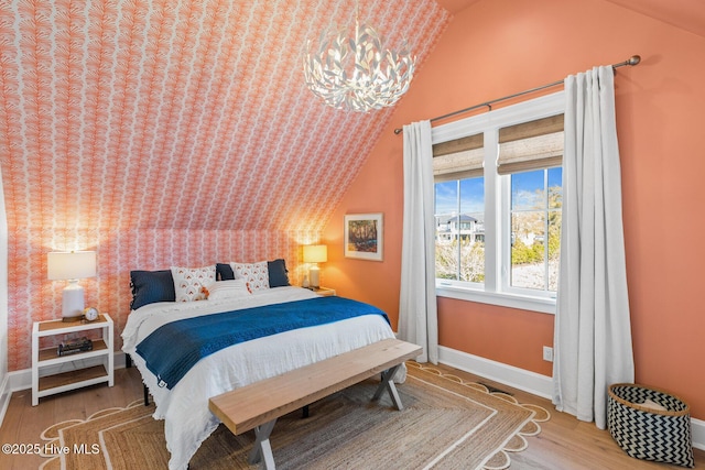 bedroom featuring hardwood / wood-style flooring, vaulted ceiling, and a chandelier