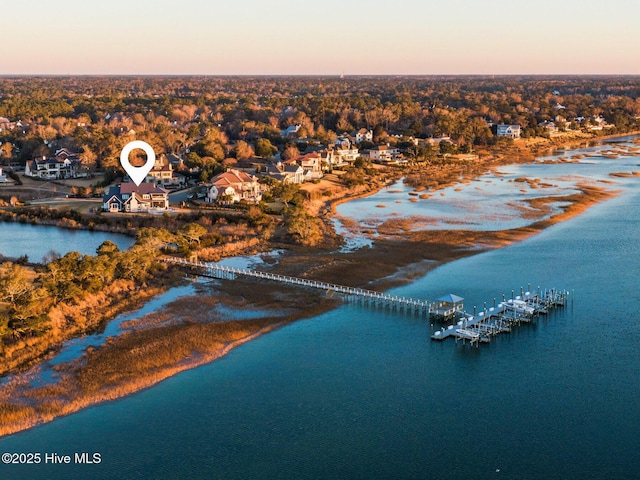 aerial view at dusk with a water view and a view of the beach