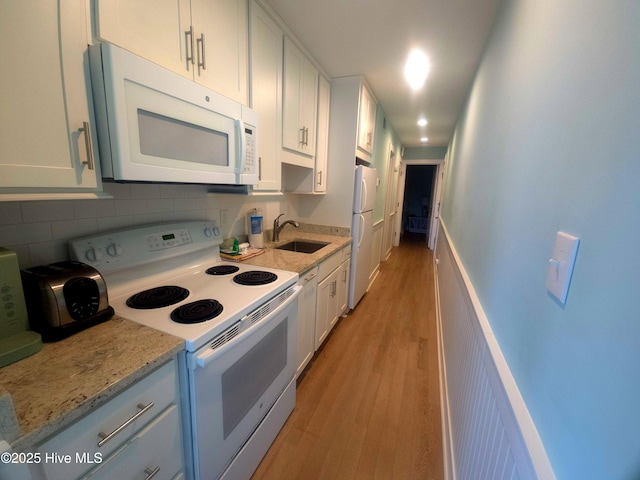 kitchen featuring sink, light stone counters, white cabinets, white appliances, and backsplash