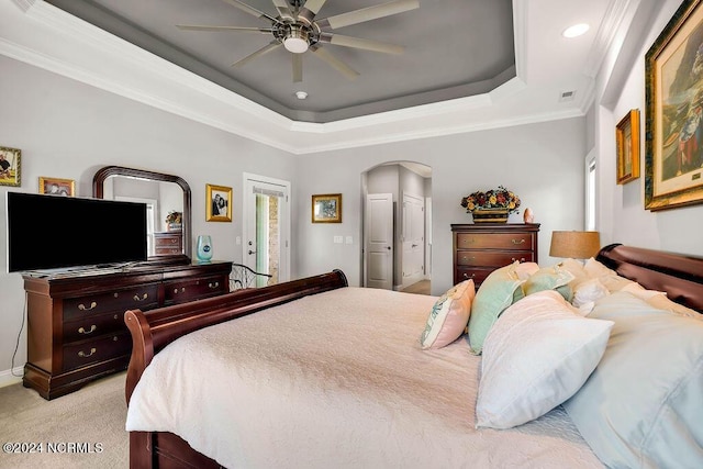 bedroom featuring crown molding, ceiling fan, a tray ceiling, and light carpet